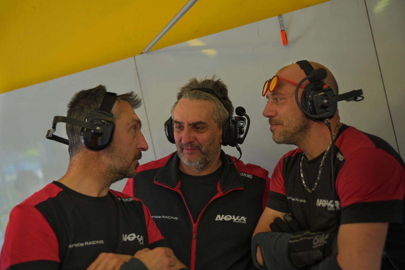 Meccanici scherzano scommettendo sul fatto che il pilota non porterà a termine la gara. (Paolo non lo sa).
